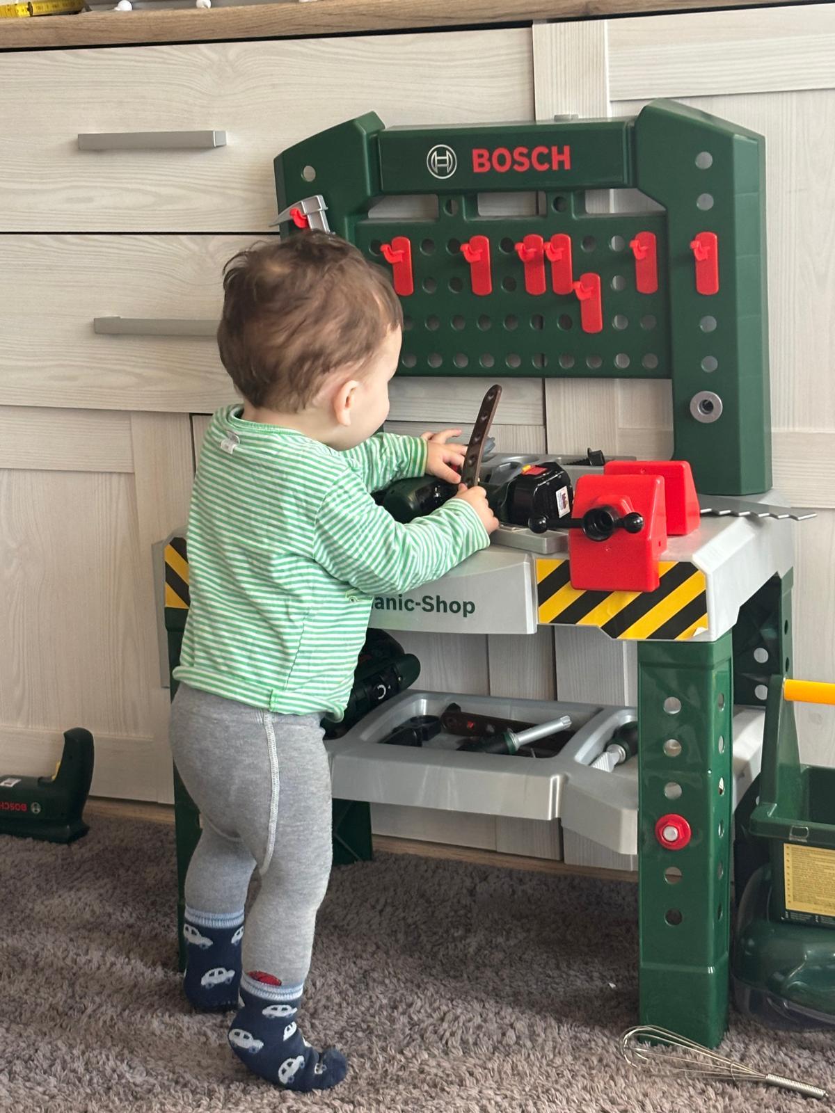 Ein Kleinkind spielt an einer Kinderwerkbank mit Werkzeugen